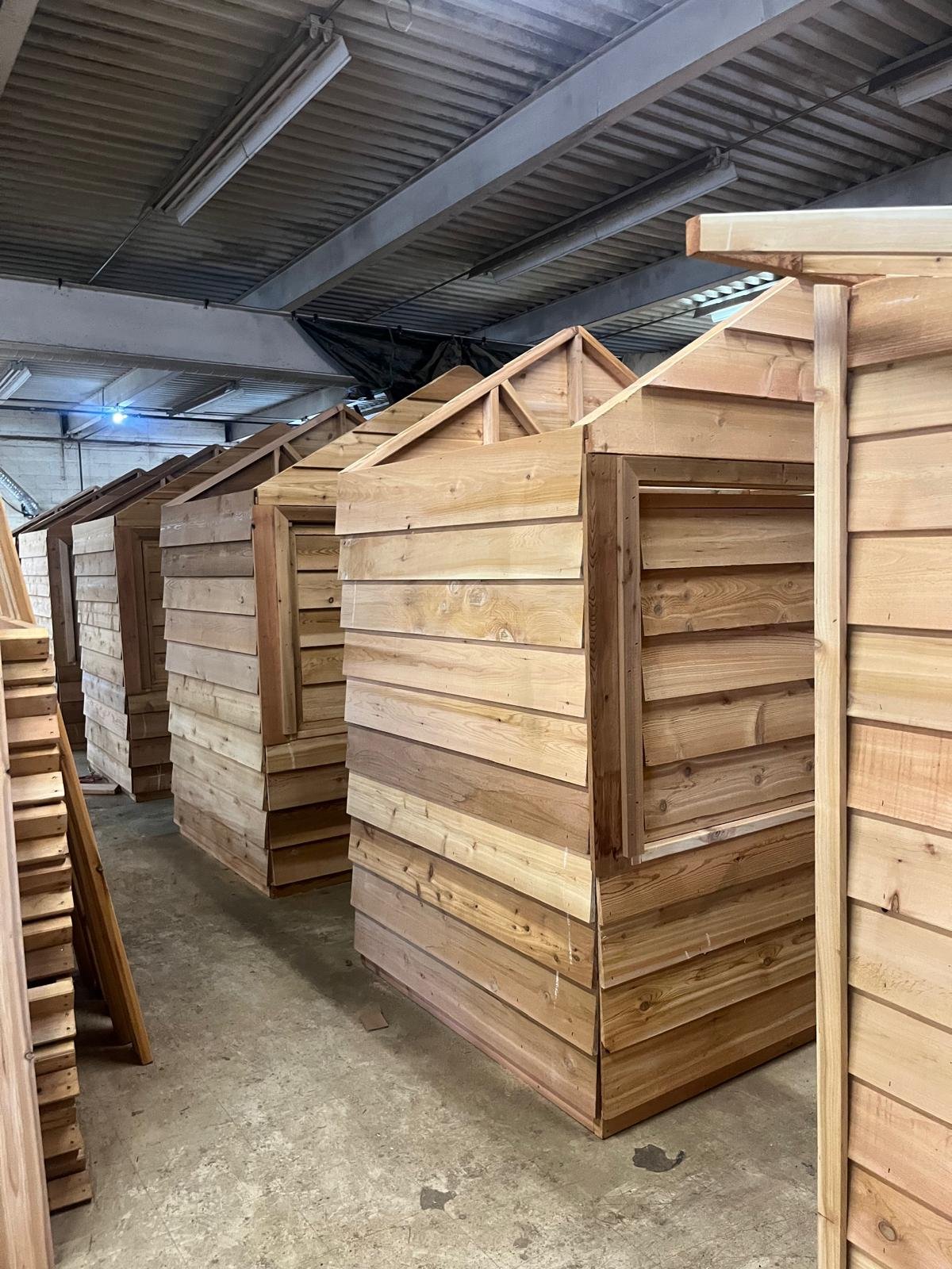 Rows of prefabricated cedar market huts in the Timberland warehouse